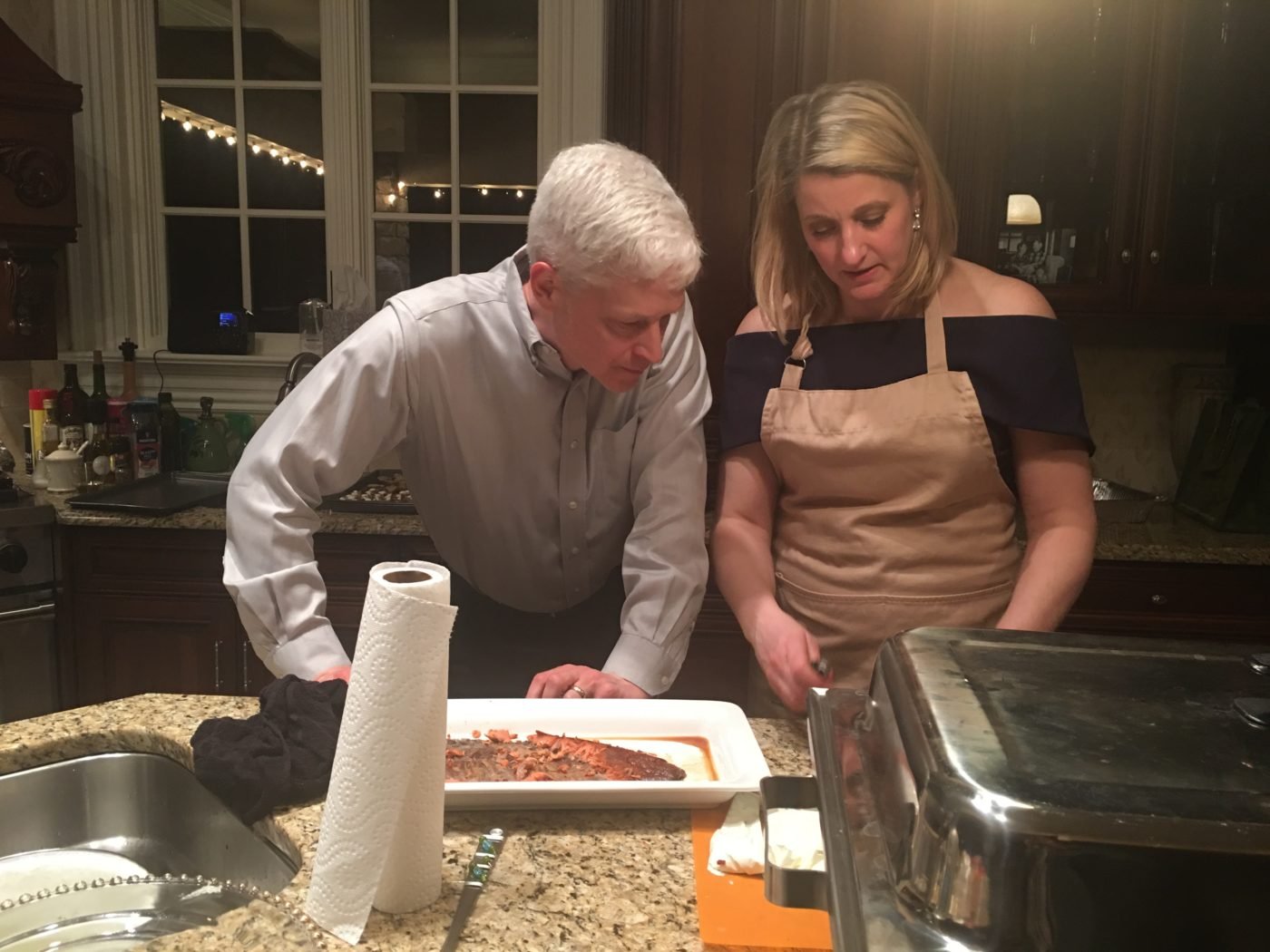 Andy and Laurie Kuzneski in kitchen preparing smoked salmon